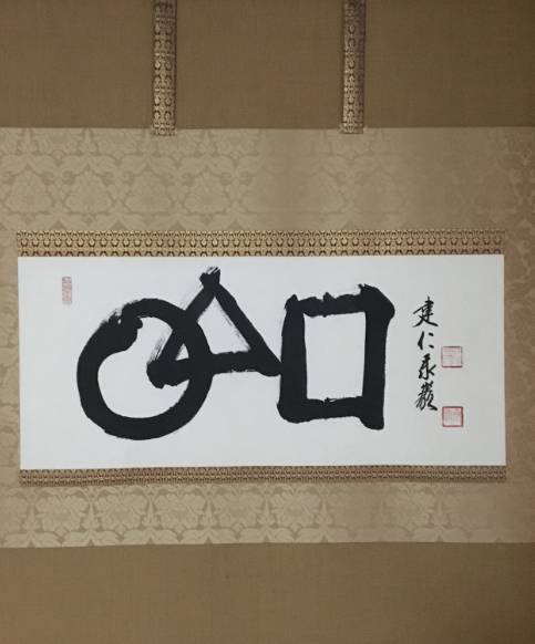 Traditional Zen calligraphy scroll featuring an enso circle and geometric brushstrokes displayed inside the meditation hall at Upaya Sangha of Tucson.